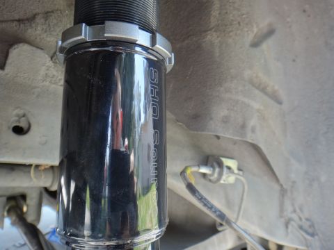 1995 Ford Taurus - A close-up view of a black coilover shock absorber, part of a vehicle's suspension system.