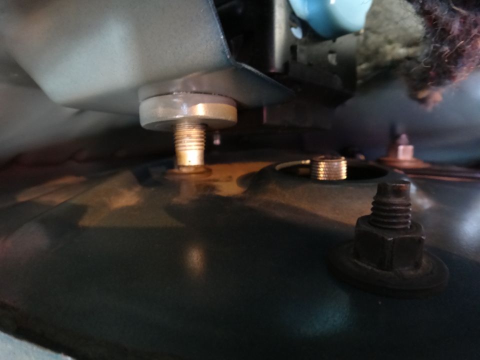 Coilover mounting bolt and nut on dark green metal surface