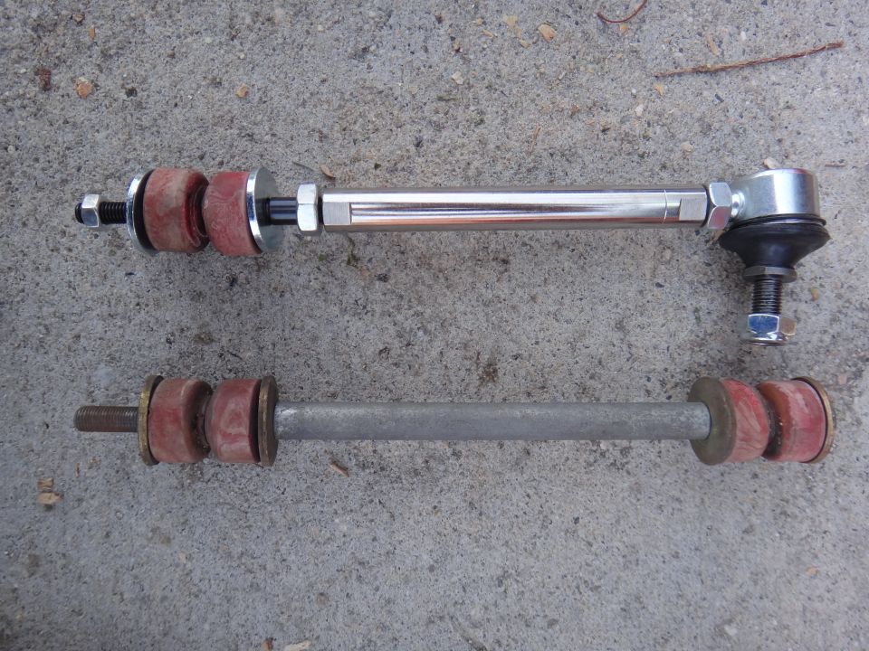 Two stabilizer links, one new chrome and one old gray, laid on concrete
