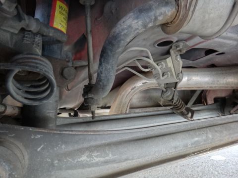1995 Ford Taurus - Close-up of the undercarriage, focusing on the rear suspension system and exhaust components.