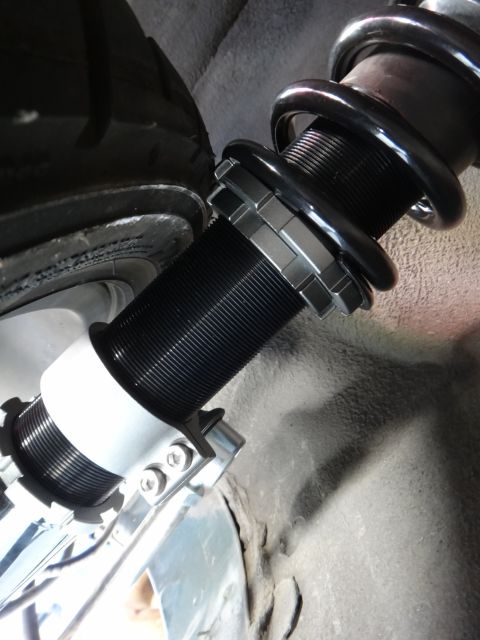 1995 Ford Taurus - Close-up of an aftermarket coilover suspension component, showing its adjustable spring perch and black coil spring.