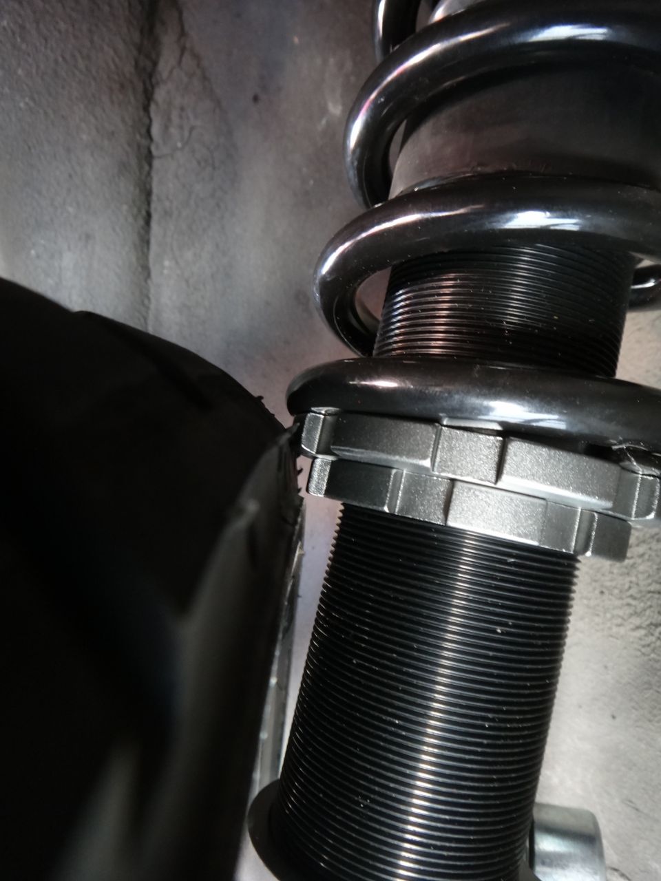 Close-up of adjustable coilover shock absorber with threaded body and locking collars