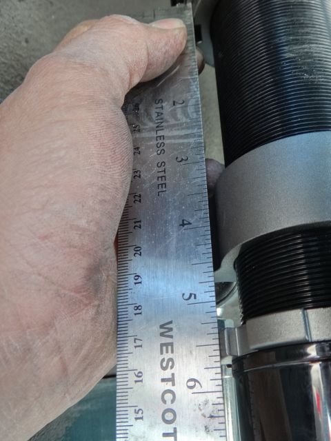 1995 Ford Taurus - A hand holds a ruler to measure a coilover shock absorber, a vehicle part.