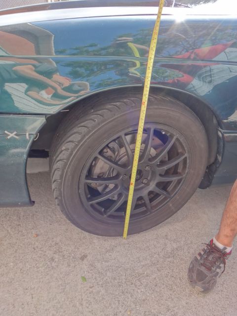 1995 Ford Taurus - Measuring the clearance of a car's wheel and fender with a tape measure.