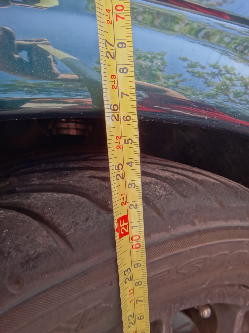 Tape measure next to a tire, showing clearance under the fender