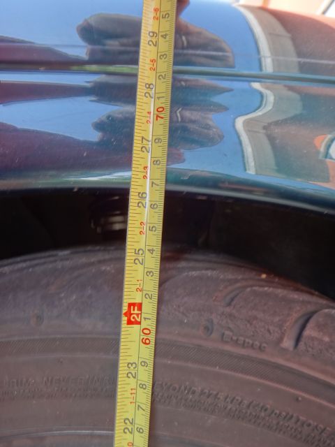 1995 Ford Taurus - A tape measure is used to check the ride height of a vehicle, with the tire and fender visible.