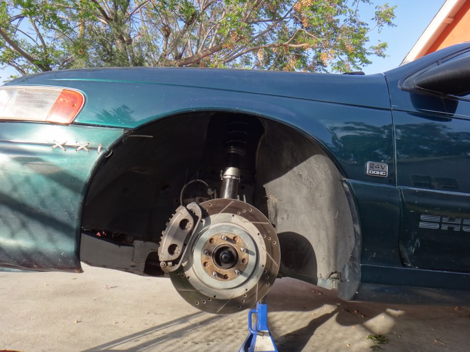Green car front wheel assembly with coilovers and slotted rotors