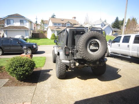 2008 Jeep Wrangler - Rear view of a gray Jeep Wrangler with a spare tire mounted on the back and a roof rack.
