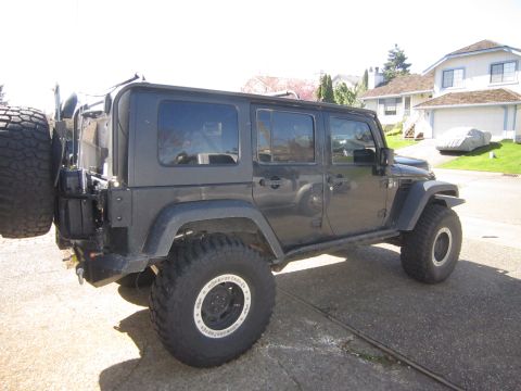 2008 Jeep Wrangler - This dark-colored Jeep Wrangler, likely a 2007 model, is shown from a 3/4 front angle with a spare tire mounted on the rear.