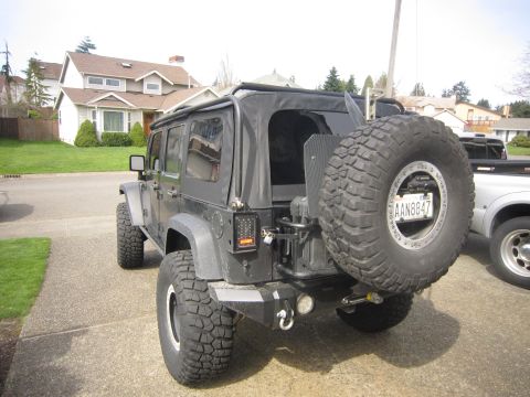 2008 Jeep Wrangler - The rear of a black Jeep Wrangler is shown, a large spare tire and a custom bumper.