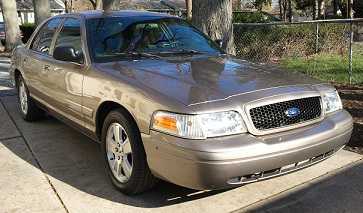 2007 Ford Crown Victoria - Tan 2007 Ford Crown Victoria sedan parked on a concrete driveway with a tree in the background.