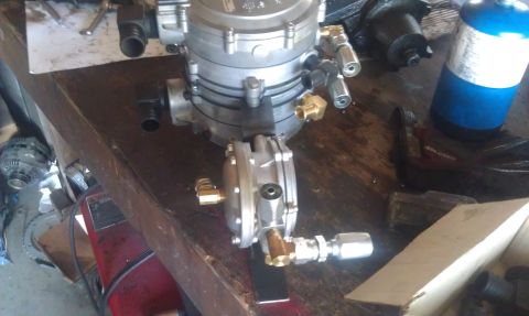 1978 Ford Bronco - A propane regulator and tank are shown on a workbench, with various fittings and a fan visible in the background.