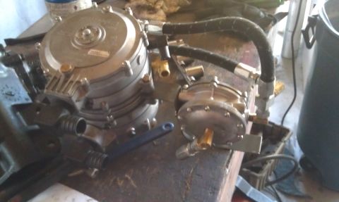 1978 Ford Bronco - Propane regulator assembly with two silver metal units and black hoses on a workbench.