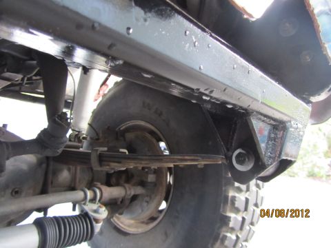 1984 Ford Bronco - Close-up view of the undercarriage of a vehicle, showing suspension components and a tire.