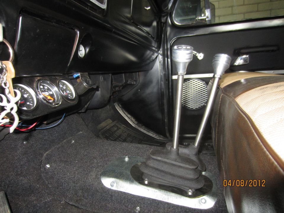 Interior shot of a vehicle showing two gear shifters, gauges on the dash, and part of a seat