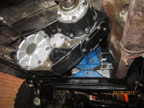 1979 Ford Bronco - Underside view of a vehicle's transmission and transfer case assembly, mounted on a blue support.