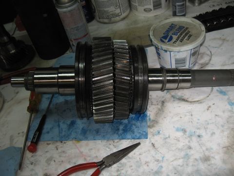 1994 Ford Bronco - Transmission input shaft with gears and a tub of Smart Blend Transmission Assembly Lube on a workbench.