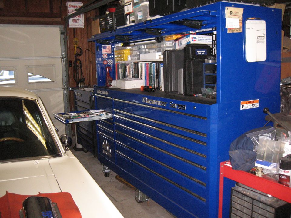 Blue Mac Tools toolbox with a red car part on its hood in a garage