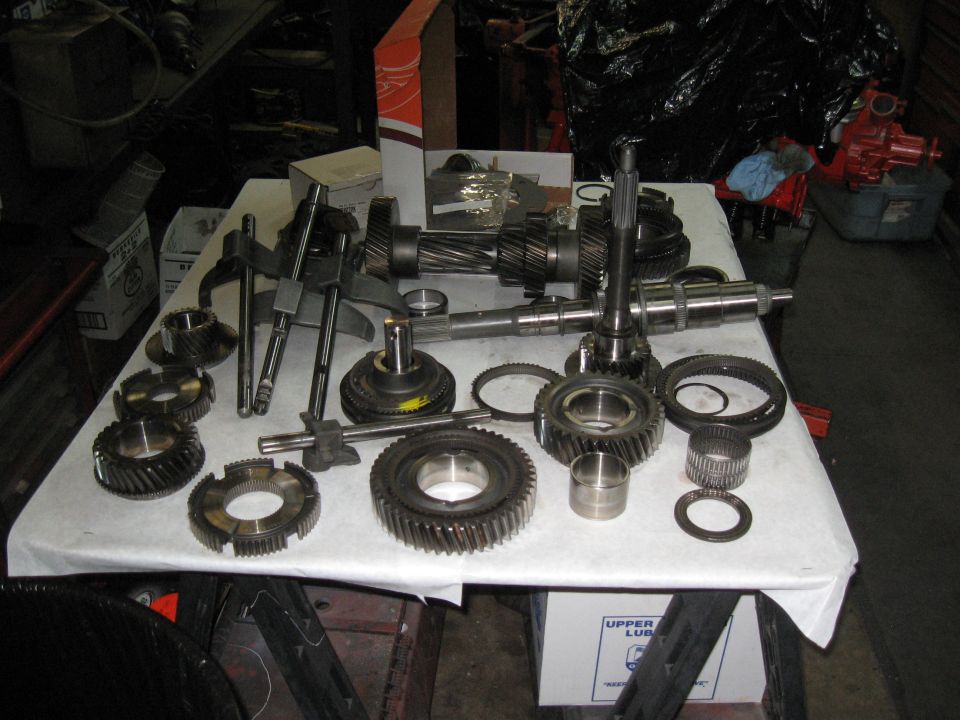 Disassembled transmission gears and shafts on a white cloth-covered table