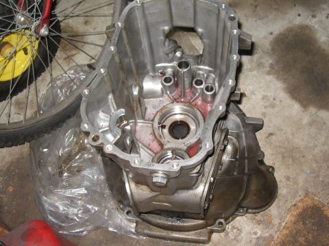 1994 Ford Bronco - The interior of a transmission casing is shown, with evidence of red fluid. A bicycle wheel is visible to the left.