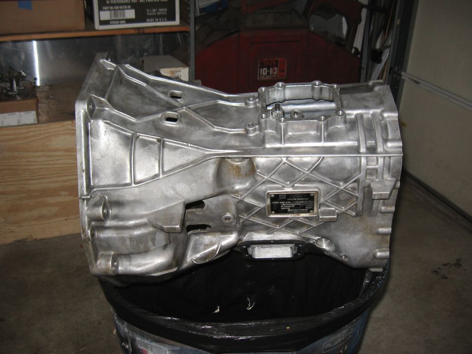 Aluminum transmission casing with a metal data plate, resting on a black trash bag