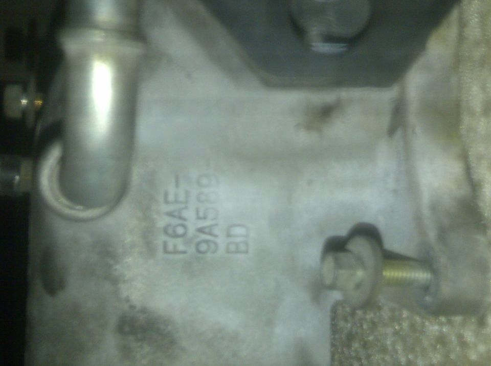 Engine part with stamped text F6AE-9A589-BD and a bolt