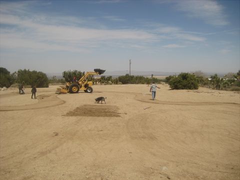 1996 Ford Bronco - Workers and a dog are in a dirt field with a tractor, possibly doing landscaping or construction.