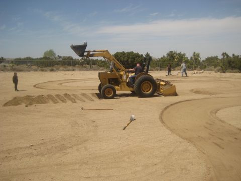 1996 Ford Bronco - A backhoe loader is being used to shape a dirt area, possibly for a track or course.