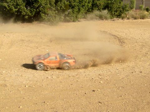 1996 Ford Bronco - Remote control truck powersliding on a dirt track, creating a large dust cloud.