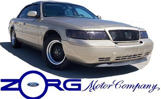 2000 Mercury Grand Marquis - A gold 2000 Mercury Grand Marquis sedan is shown from the front 3/4 angle with a white background and Zorg Motor Company logo.