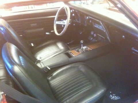 1968 Chevrolet Camaro - The interior of a 1968 Chevrolet Camaro features black vinyl seats, a wood-grain center console, and a white steering wheel.