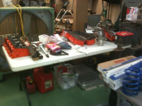 1968 Chevrolet Camaro - Various automotive parts and tools are laid out on a folding table in a cluttered workshop.