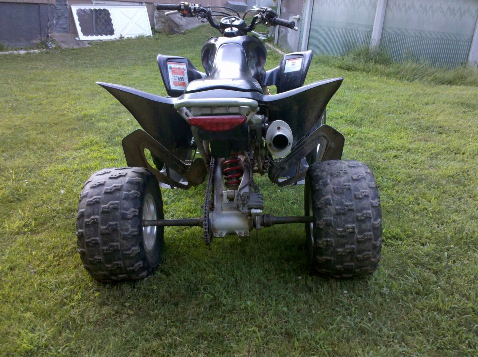 Rear view of a sport ATV quad with paddle-style tires parked on grass
