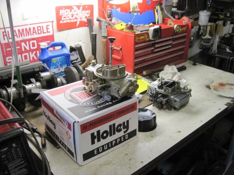 1978 Ford Bronco - A Holley carburetor is shown in its box on a workbench, alongside another carburetor and various tools and supplies.