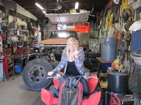 1978 Ford Bronco - Woman on ATV in a cluttered garage with an orange 1977 Ford F-Series truck behind her.