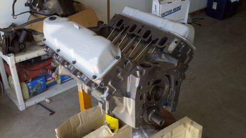 1978 Ford Bronco - A V8 engine block is shown on an engine stand, with various automotive parts visible in the background.