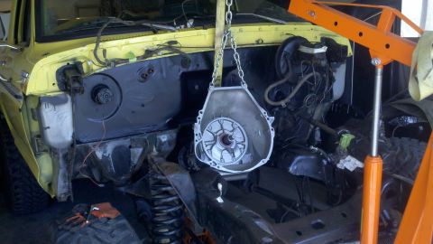 1978 Ford Bronco - The engine bay of a 1978 Ford Bronco is shown with the engine out and transmission being worked on.