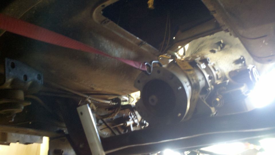 Underside of a vehicle with a transmission being supported by a red strap