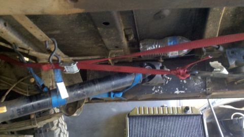 1978 Ford Bronco - Vehicle's undercarriage with driveshaft and straps, possibly during a repair or transport.