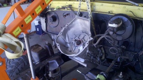 1978 Ford Bronco - Transmission housing being removed from a vehicle's engine bay with an engine hoist.