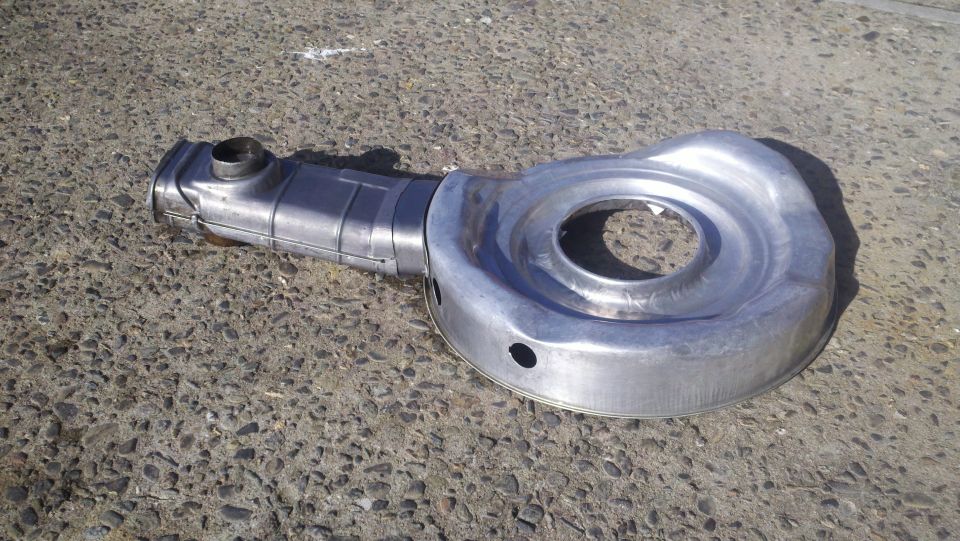 Metal air cleaner assembly with a curved intake tube, resting on concrete