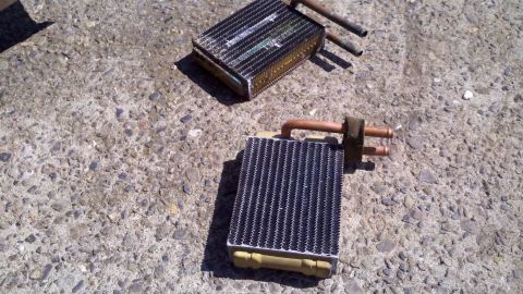 1978 Ford Bronco - Two vehicle heater cores are shown on a concrete surface, possibly for replacement or repair.