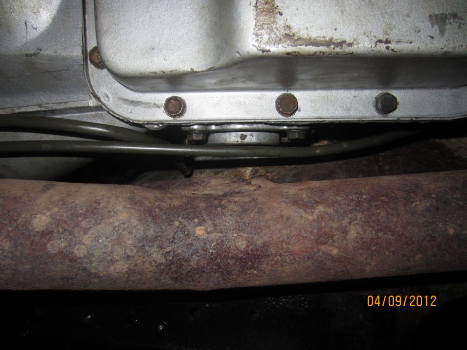 Close-up of a transmission pan and rusted exhaust pipe
