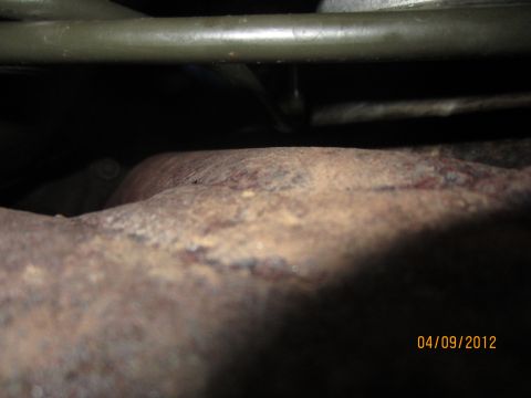 1979 Ford Bronco - Close-up view of undercarriage components, including a rusty exhaust pipe and frame.