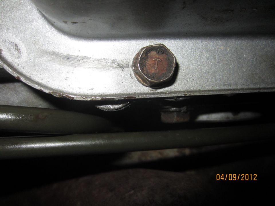 Close-up of a bolt on a metal casing, with two dark pipes below it. Date stamp reads 04/09/2012