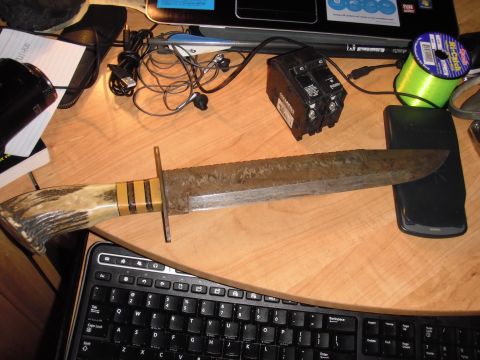 1993 Ford Bronco - A large, rusty knife with an antler handle is placed on a desk with various items.