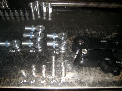 1996 Ford Bronco - Various automotive linkage parts, including rod ends and black steering components, are laid out on a metal surface.
