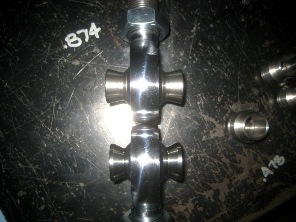 two shiny metal universal joints stacked on a dark surface with markings .874 and .478