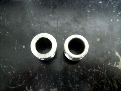 1996 Ford Bronco - Two metal bushings are shown against a dark, textured background.