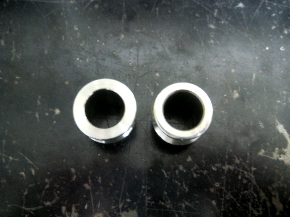 Two metal bushings on a dark surface
